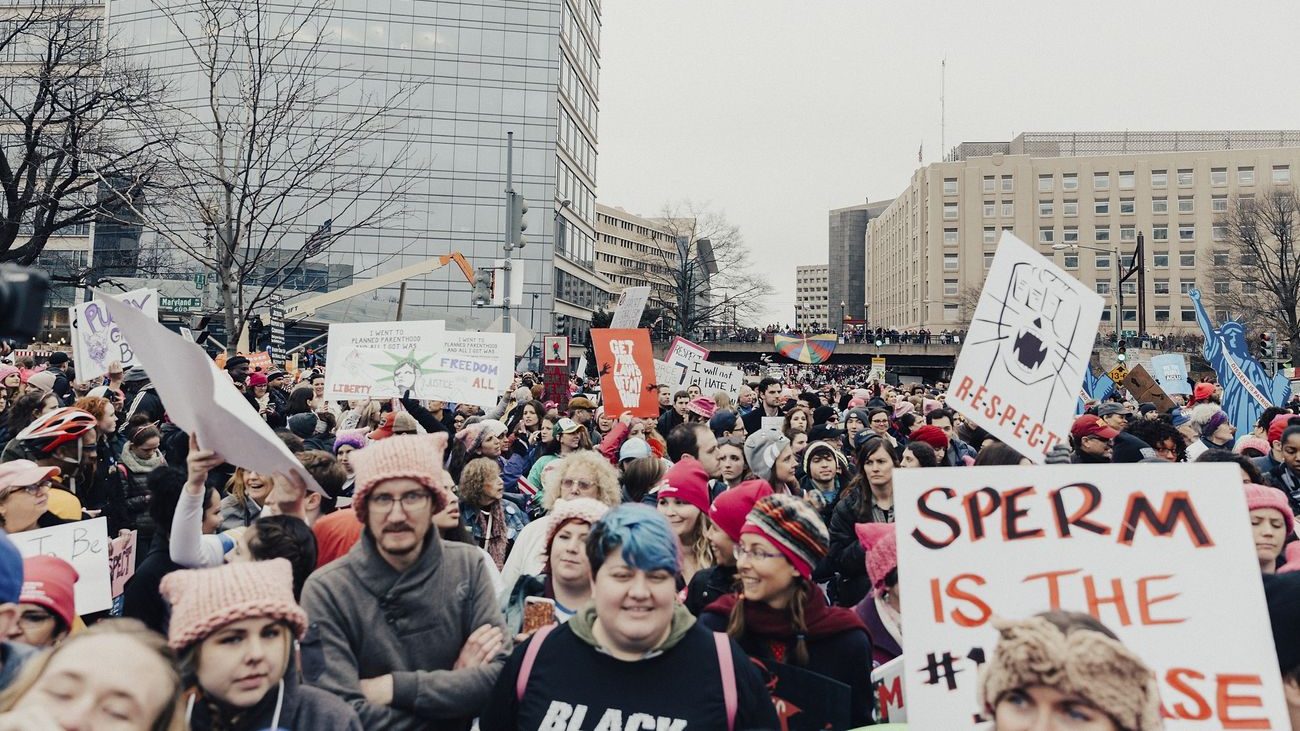 Protesters march wearing pink hats and carrying signs with slogans like "Get Your Laws Off My Body" and "R-E-S-P-E-C-T"